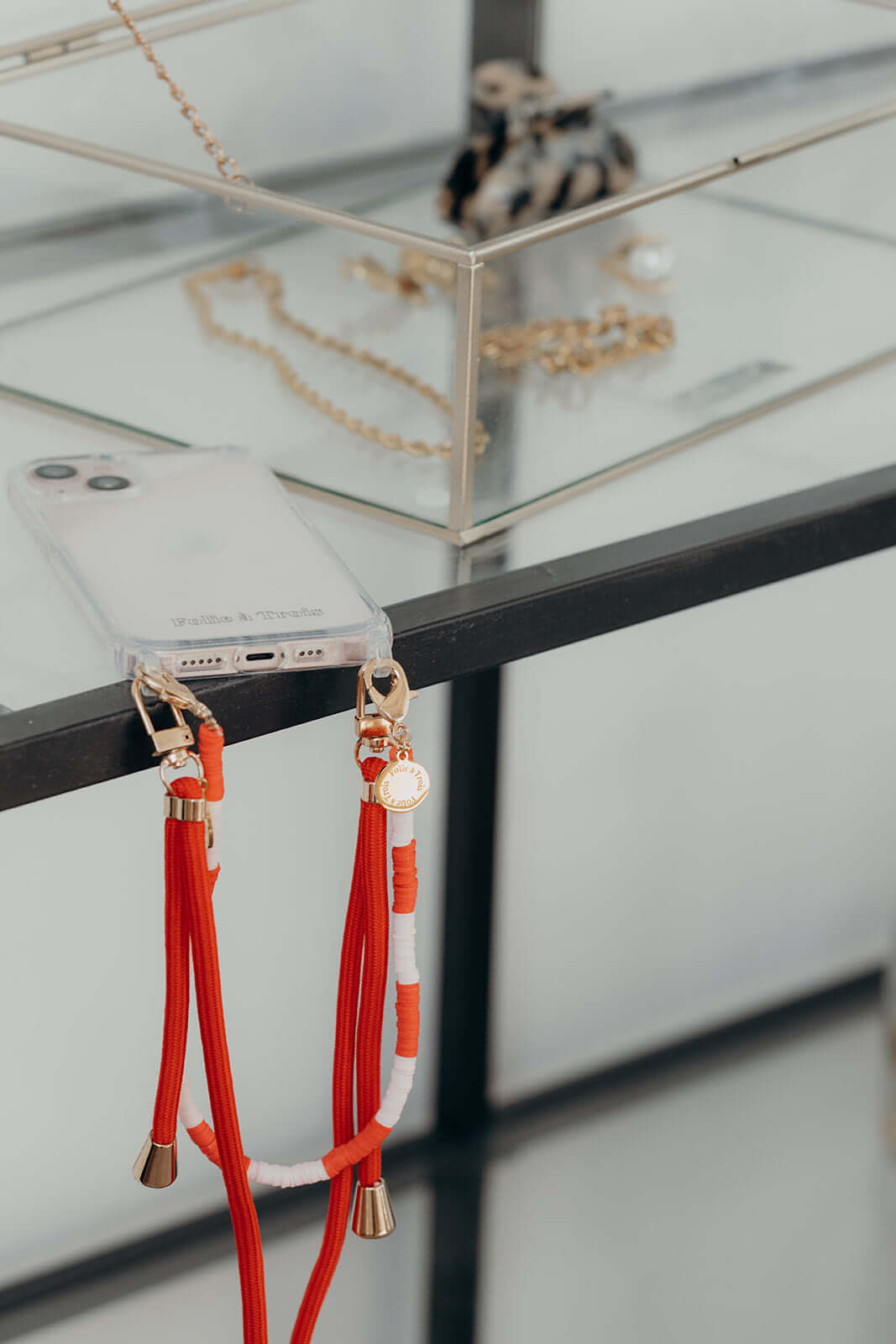 Close-up of orange and white Colorful PHONE CORD clasps hanging from a glass display shelf.