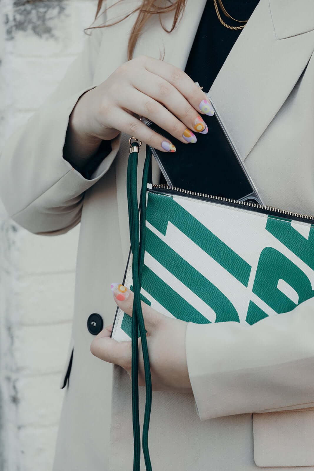 Dark green Colorful PHONE CORD, phone tucked into a green and white striped clutch bag.