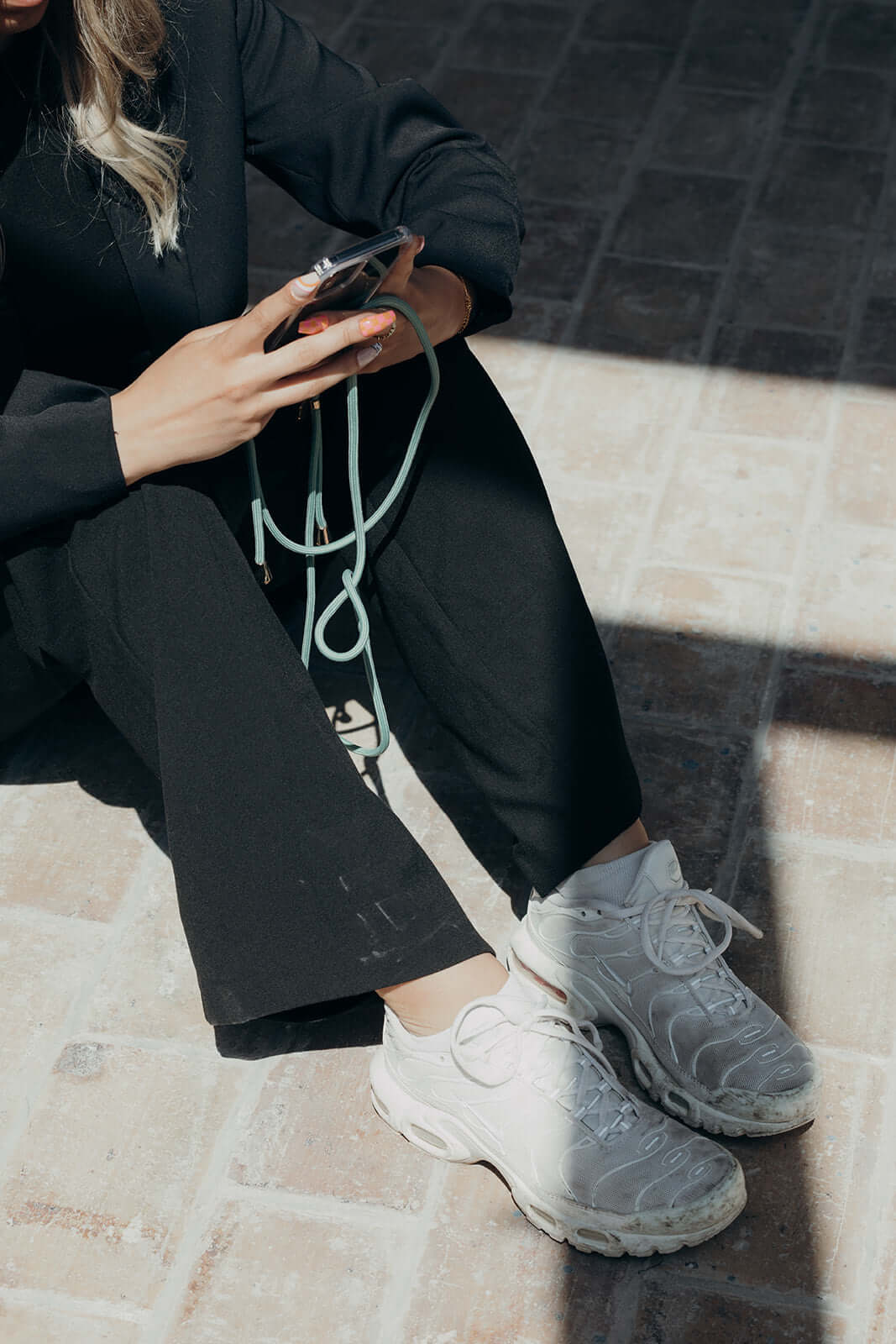 Sage green Colorful PHONE CORD, model seated wearing white sneakers, phone in hand.