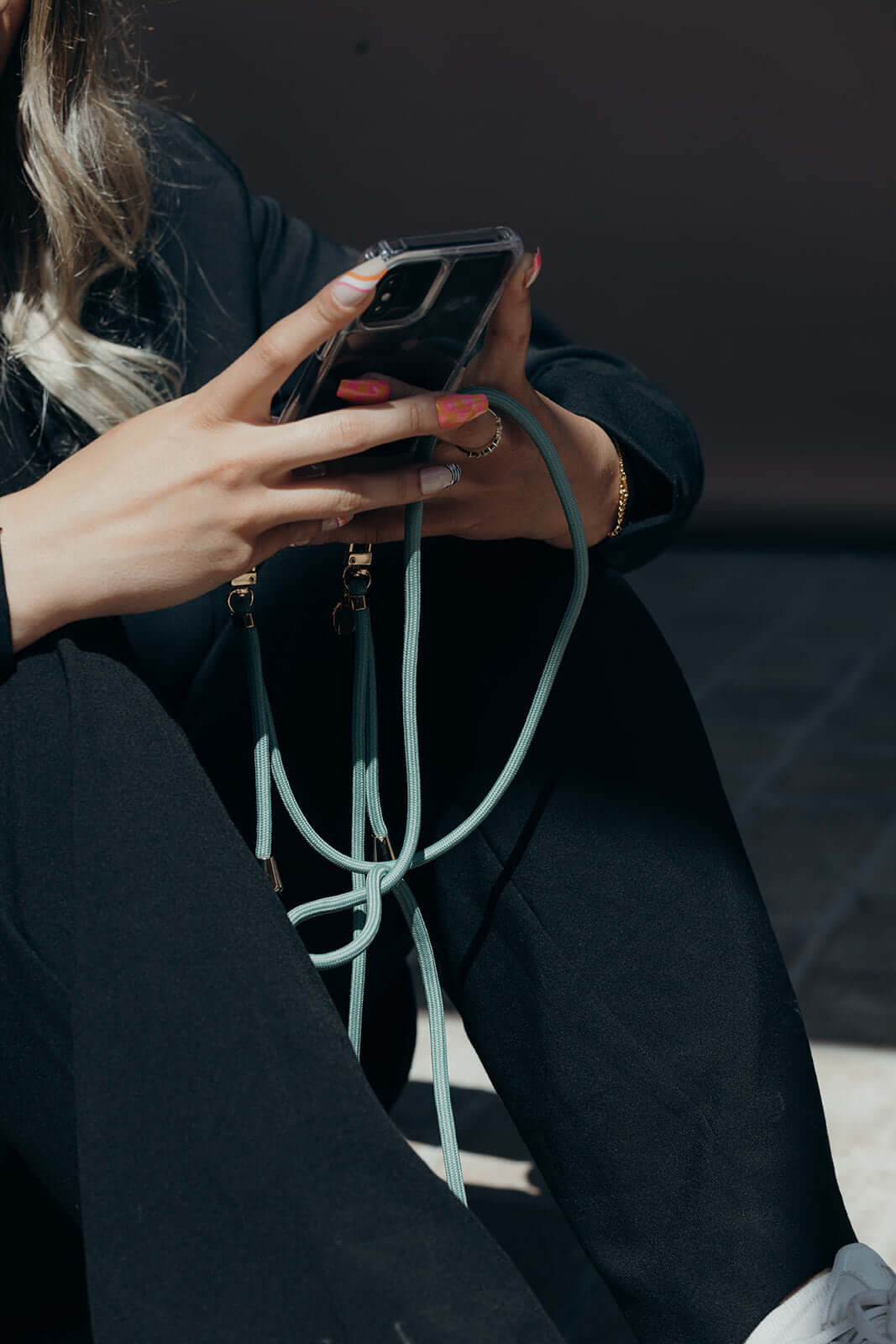 Close-up of a mint green Colorful PHONE CORD wrapped around a model's hand holding her phone.