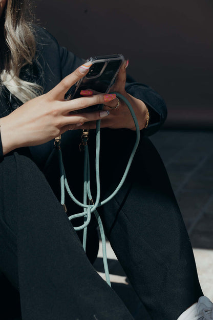 Close-up of a mint green Colorful PHONE CORD wrapped around a model's hand holding her phone.