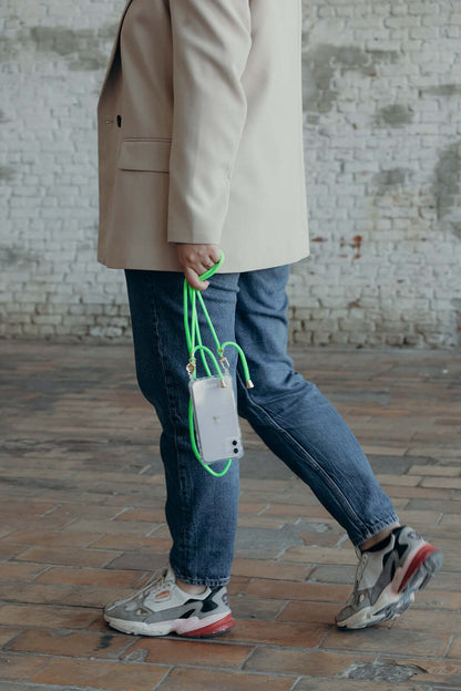 Neon green Colorful PHONE CORD, model walking in denim jeans while holding her phone.