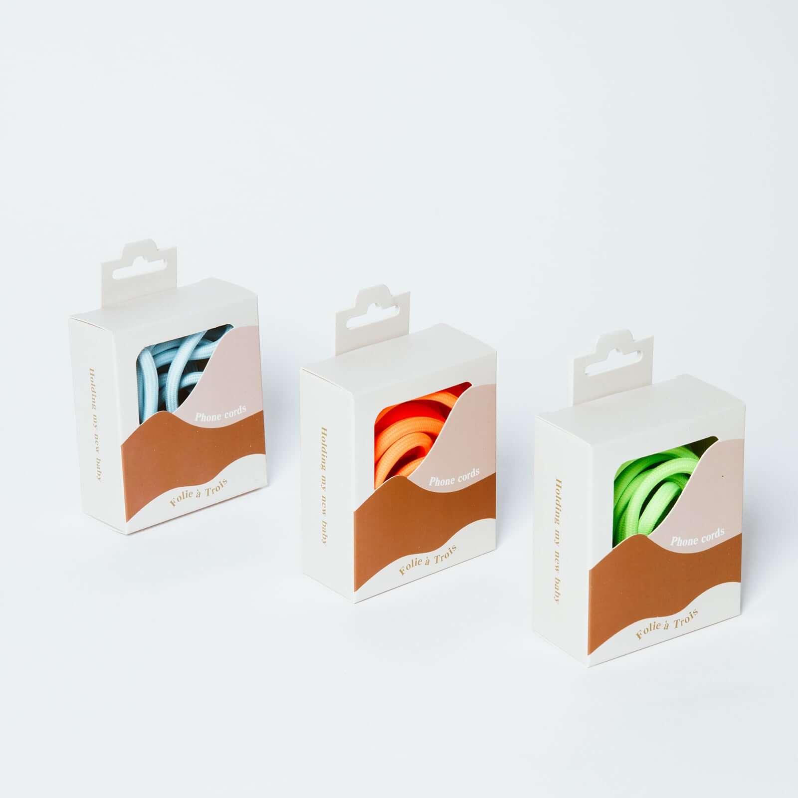 Three Colorful PHONE CORD packaging boxes showing blue and white striped, orange and bright green cords.