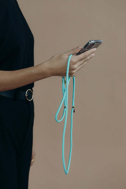 Teal Colorful PHONE CORD, model holding her phone in hand against a tan background.