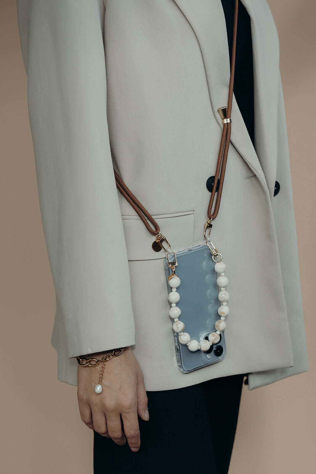 Tan Colorful PHONE CORD paired with a white beaded strap, phone worn on the hip over a beige blazer.