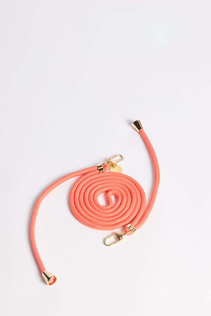 Coral Colorful PHONE CORD coiled with gold-tone hardware, shown from another angle on white.