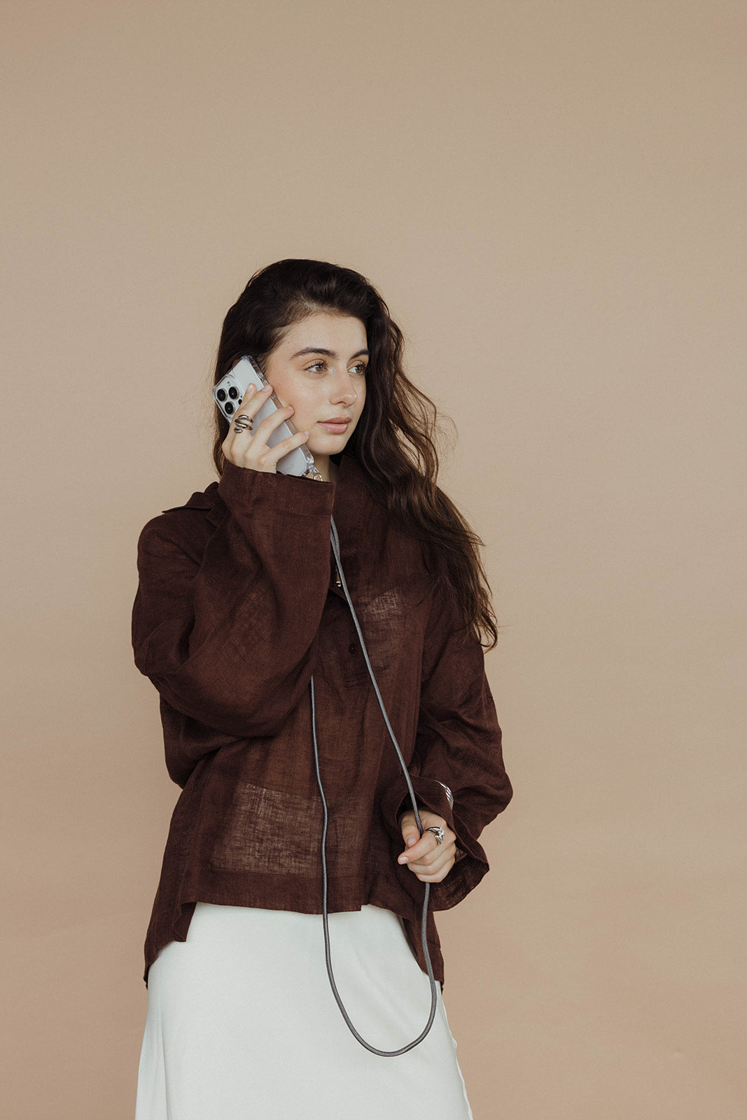Model in a brown linen outfit on a phone call, dark gray Colorful PHONE CORD visible.