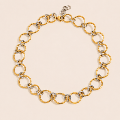 Two-tone Contradiction NECKLACE with linked gold and silver circles forming a chunky chain, laid flat on beige.
