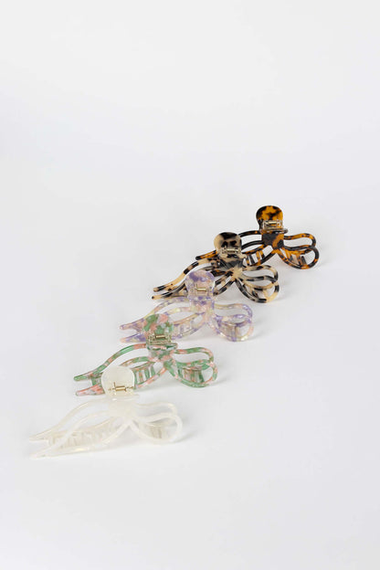 Coquette HAIR CLIP five bow-shaped claw clips in amber, dark tortoise, lilac, green-pink and cream colorways, studio shot.