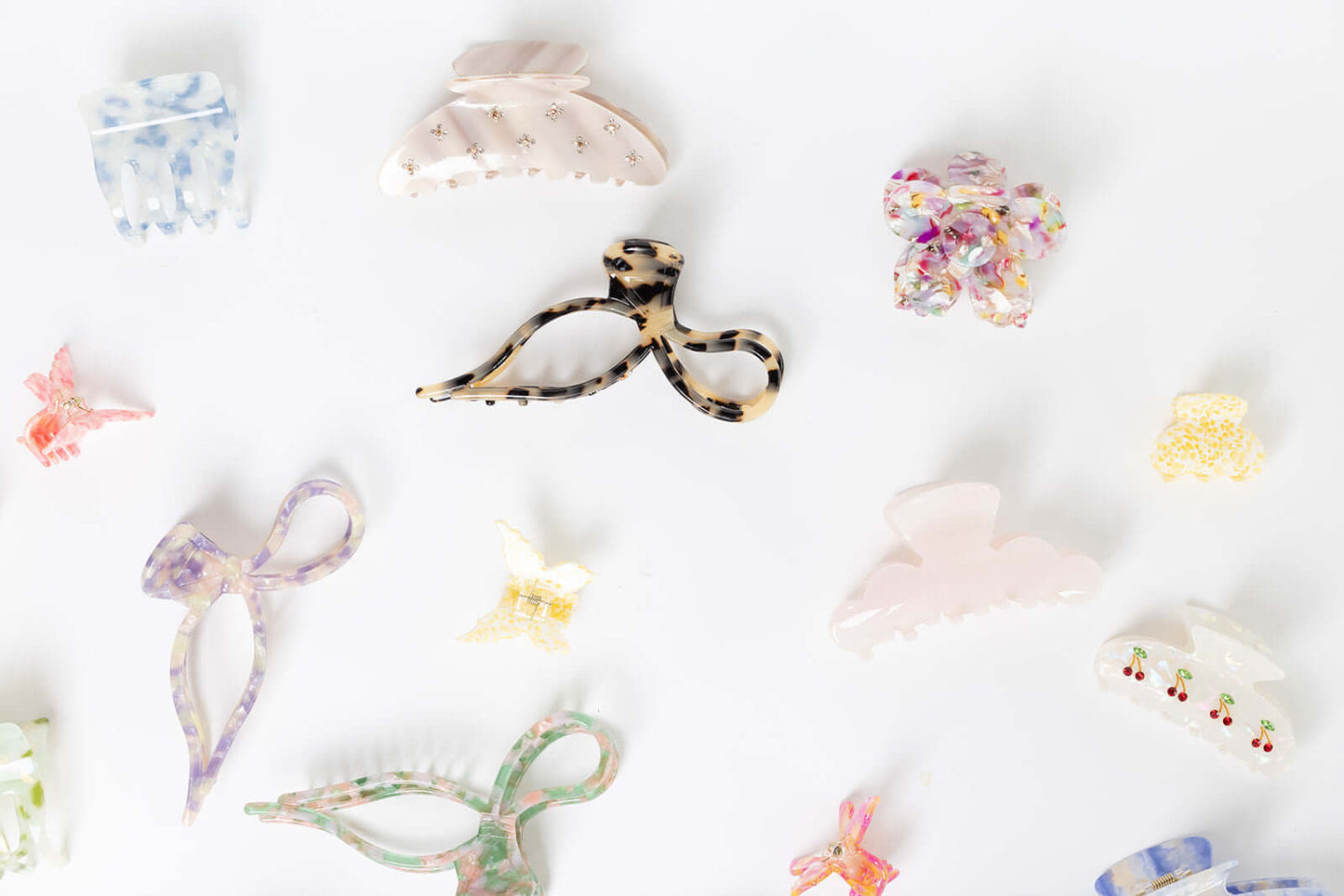 Coquette HAIR CLIP shown among a wide flat-lay assortment of differently shaped acetate hair clips in various colors and patterns.