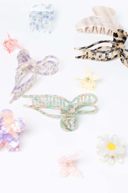 Coquette HAIR CLIP shown among a closer flat-lay assortment of differently shaped acetate hair clips in various colors and patterns.