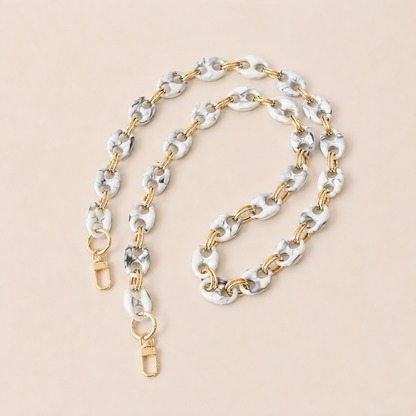White and black marbled coin-link phone chain with gold connectors coiled on cream — Folie à Trois Corvin wholesale phone chain