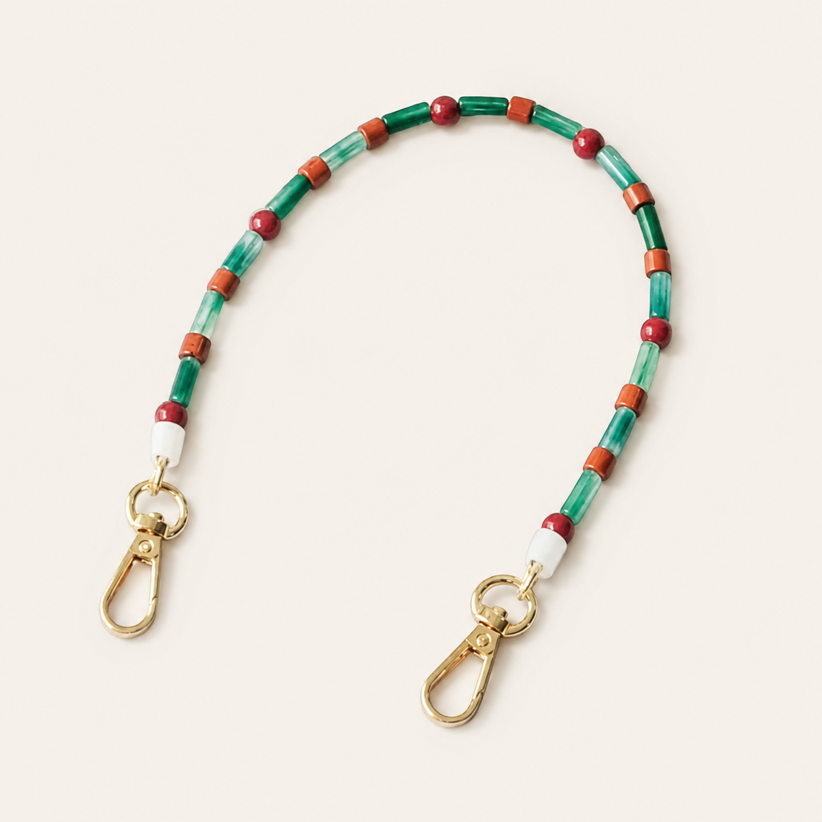 Green and maroon beaded Cosmo short phone strap coiled flat with gold-tone clasp ends.