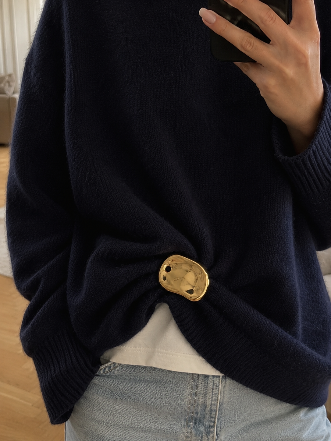 Model wears a gold Costa BROOCH cinching a navy sweater at the waist over jeans, mirror selfie — Folie à Trois