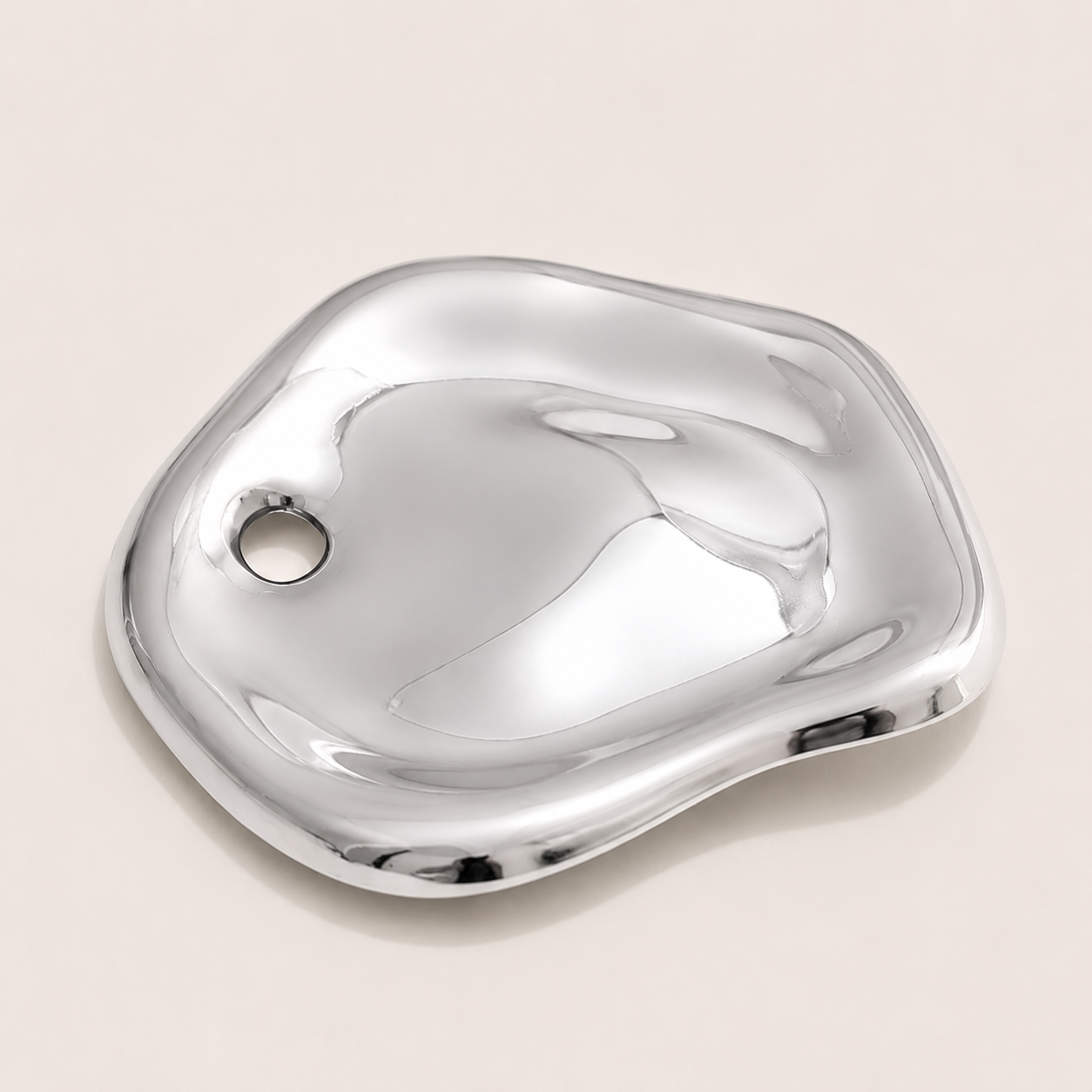 Silver molten pebble-shaped brooch with a rounded pierced detail on a cream backdrop — Folie à Trois Costa BROOCH