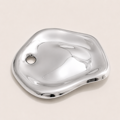 Silver molten pebble-shaped brooch with a rounded pierced detail on a cream backdrop — Folie à Trois Costa BROOCH
