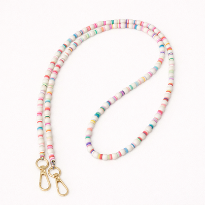 White beaded Cove LONG PHONE CHAIN with colorful striped accent beads and a gold clasp, shown as a flat lay.