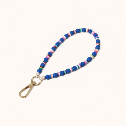 Blue beaded Cove SHORT PHONE STRAP with colorful striped accent beads and a gold clasp, shown as a flat lay.