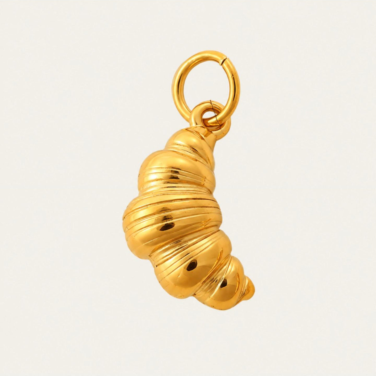 The Croissant CHARM in gold, a sculpted croissant-shaped pendant with layered detail, shown in close-up product photography.
