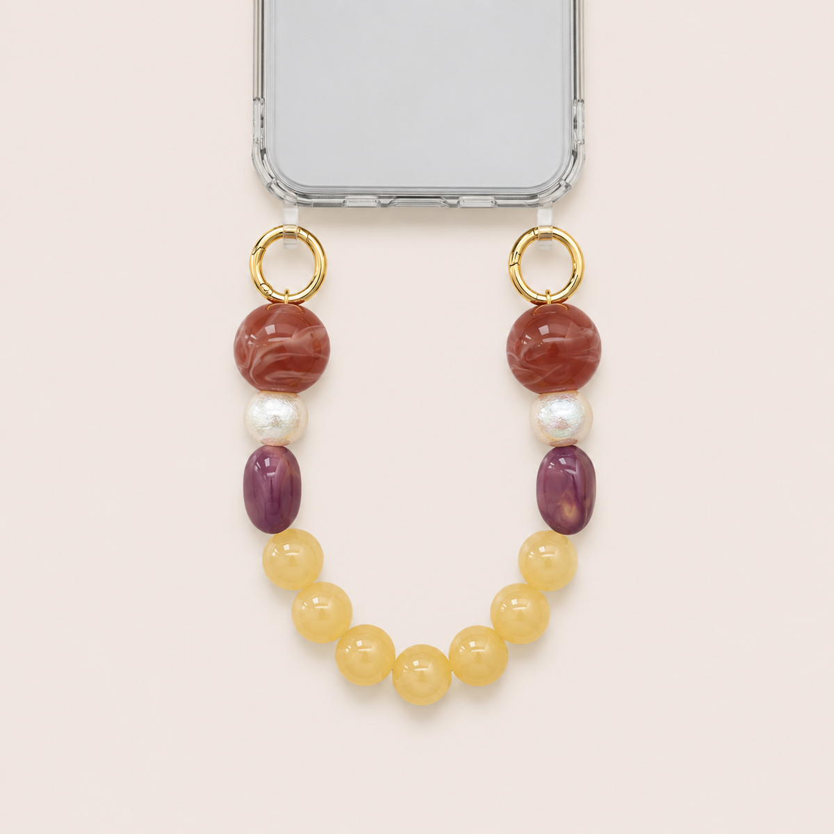 Red, pearl, purple, and yellow bead phone chain clipped to a clear iPhone case on cream — Folie à Trois Delphine wholesale phone chain