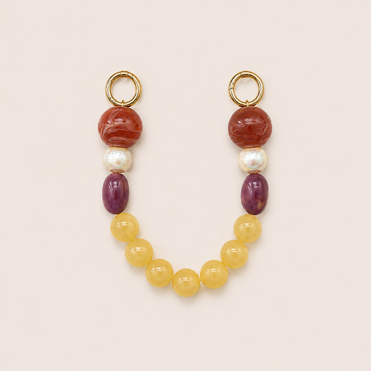 Red, pearl, purple, and yellow bead phone chain with gold hoop clasps laid flat on cream — Folie à Trois Delphine wholesale phone chain