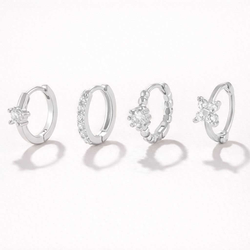 Desiree Set in silver tone, the same four huggie hoop styles with solitaire, pave, beaded flower, and clover crystal details.