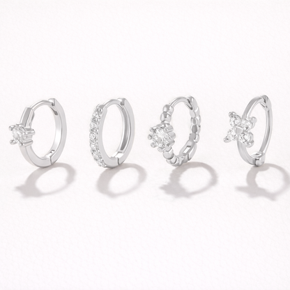 Desiree Set in silver tone, the same four huggie hoop styles with solitaire, pave, beaded flower, and clover crystal details.