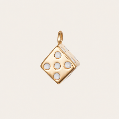 The Dice CHARM in gold, a cube-shaped pendant set with white enamel pips, shown in close-up studio photography on cream.