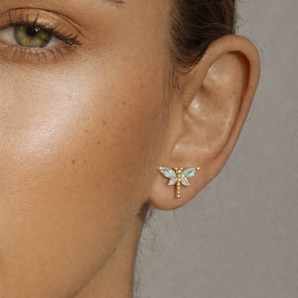 Worn on a model's ear, the Dragonfly EARRINGS perch delicately with blue crystal wings catching the light.