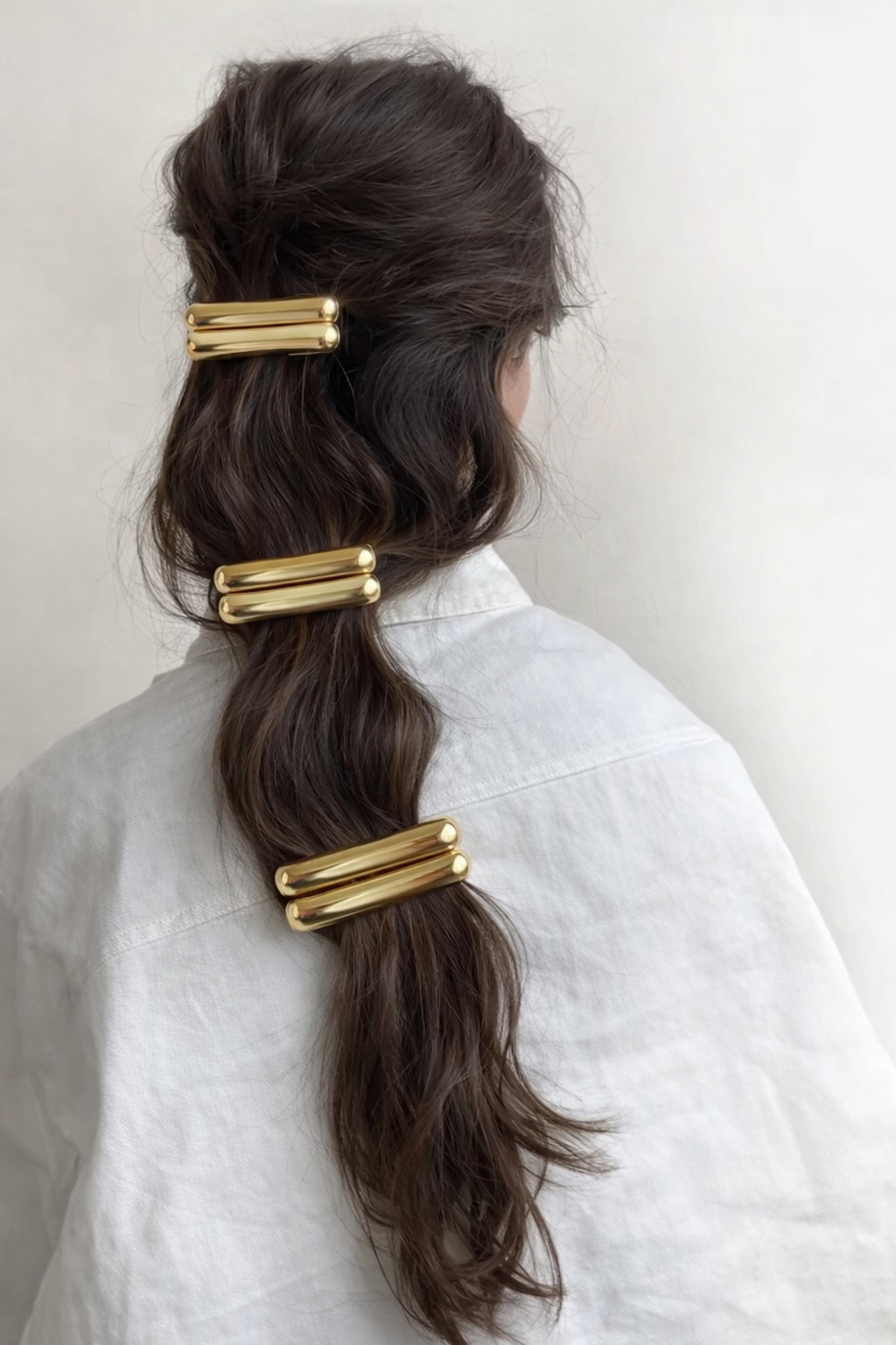 Dua HAIR CLIP three gold-tone barrettes styled down a wavy brunette braid, back view.