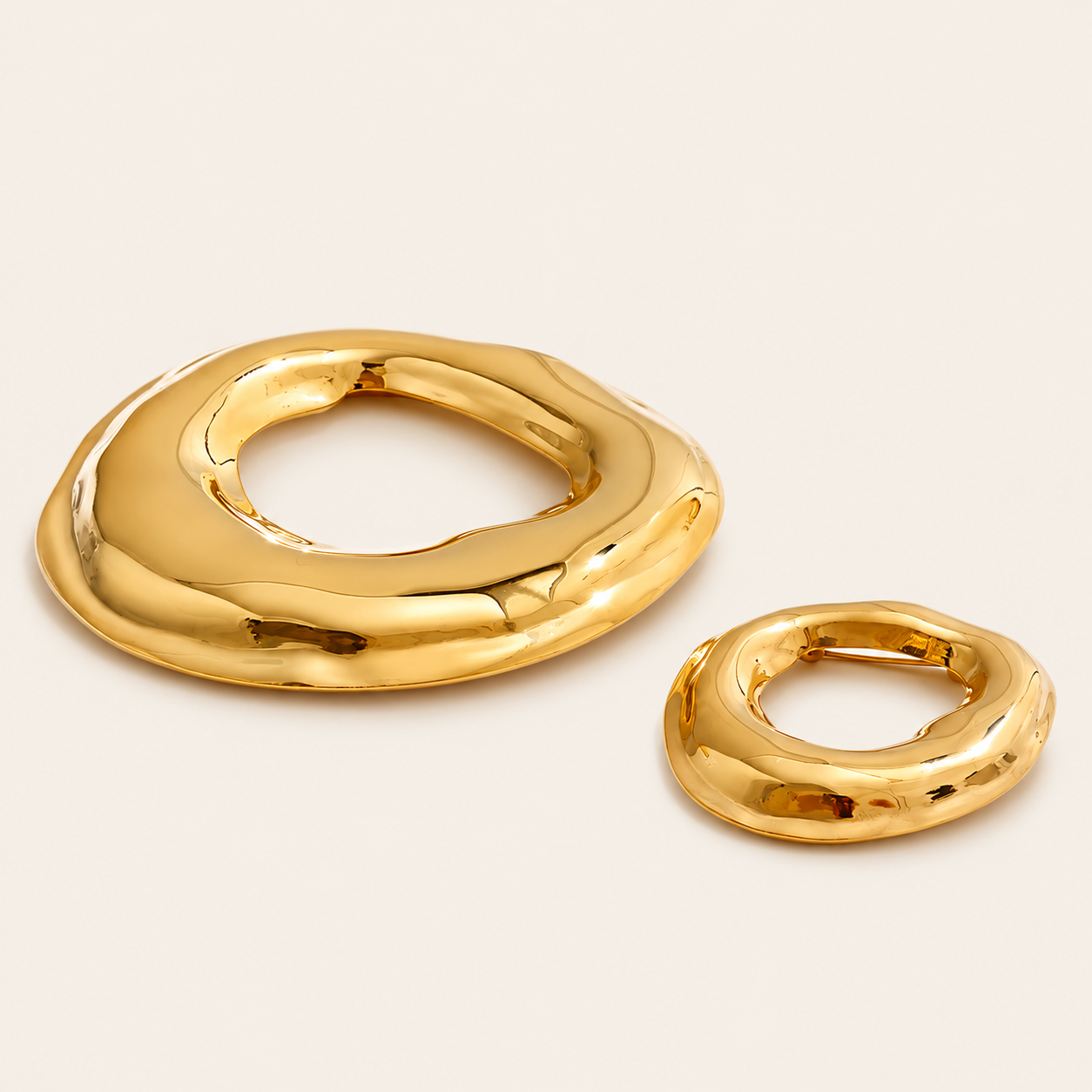 Gold molten organic-shaped ring brooches in two sizes shown side by side on a cream backdrop — Folie à Trois Duna BROOCH