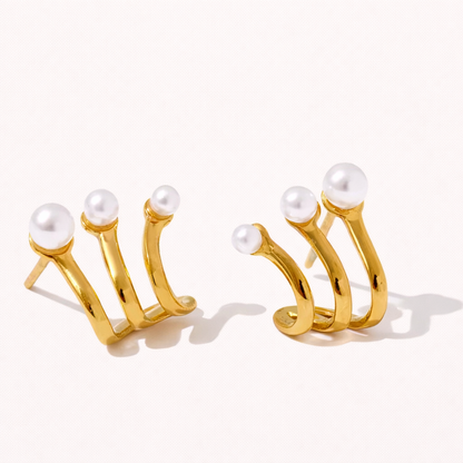Effie Earrings in gold, three curved prongs each topped with a graduated pearl, fanning out from the lobe like a claw design.