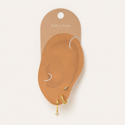 Illustrated Folie a Trois earring card showing the Eira Set pieces arranged on an ear-shaped display, hoop, huggie, and stud.