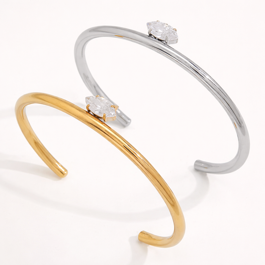 Electric Frost BRACELET pair in gold and silver, open cuffs each set with a single marquise crystal, shown together.