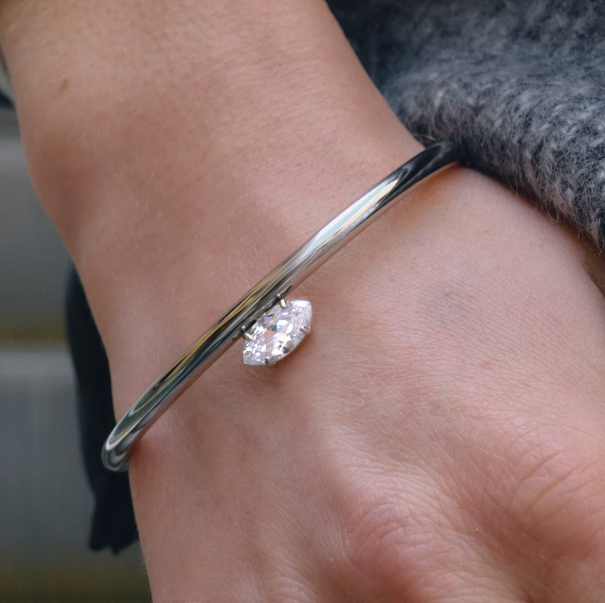Electric Frost BRACELET in silver worn on the wrist, close-up with a grey knit sweater sleeve pushed back.