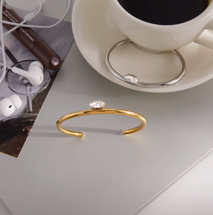 Electric Frost BRACELET in gold styled on a desk beside a coffee cup, earbuds, and an open magazine.