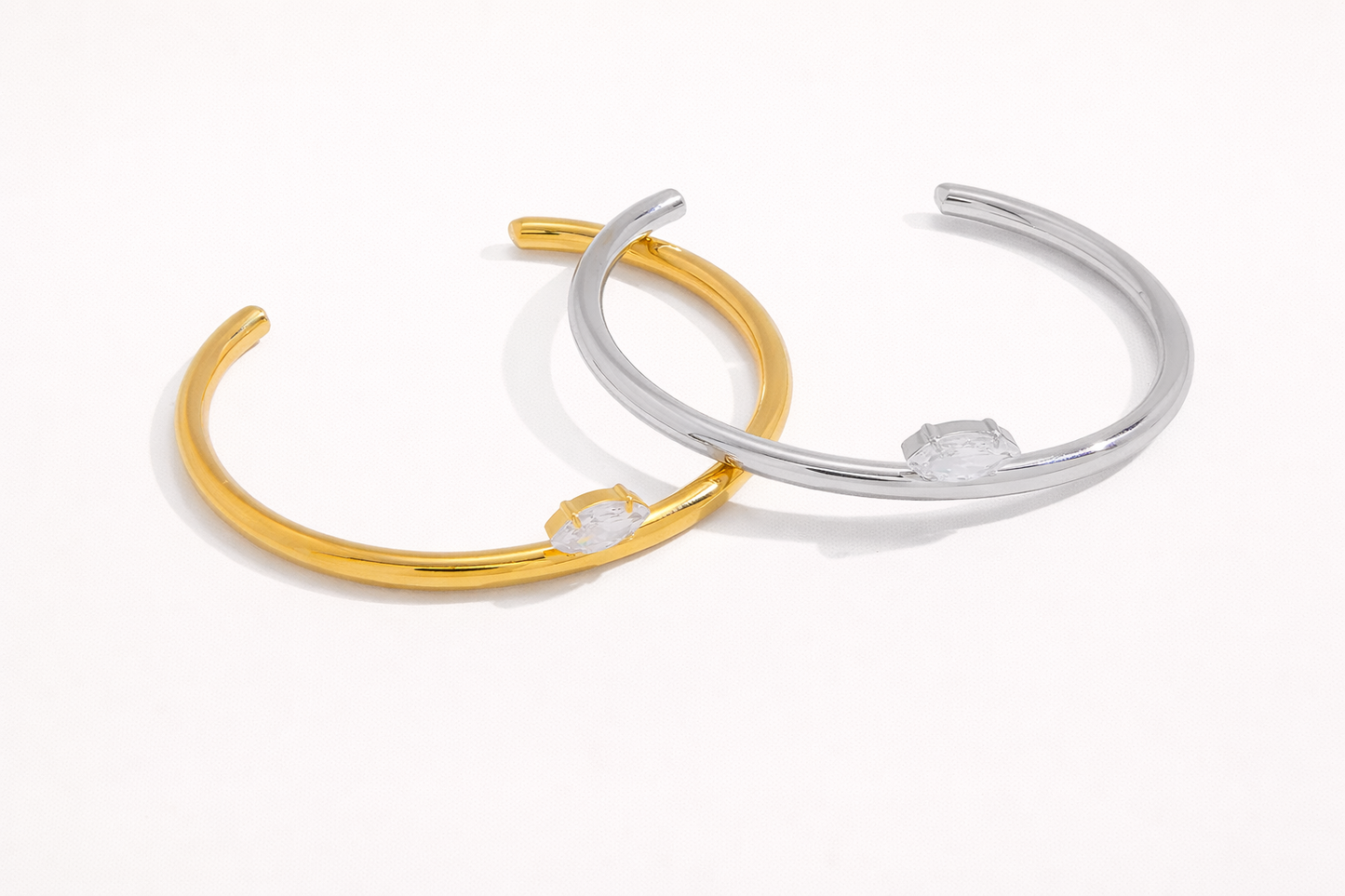 Electric Frost BRACELET pair in gold and silver, open cuffs crossed together, each set with a marquise crystal.
