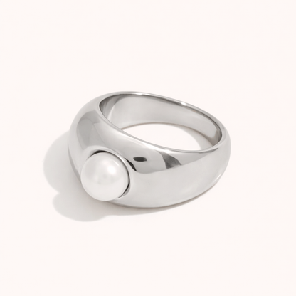 Chunky silver dome ring set with a single pearl, shown at an angle on a cream backdrop — Elka RING.