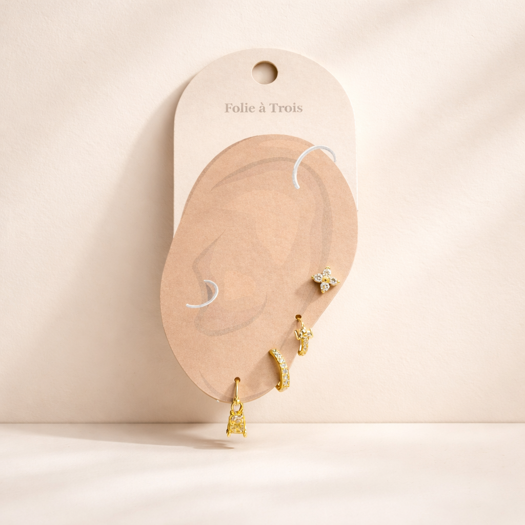 The Elle SET is displayed on a branded card shaped like an ear, showing the gold pieces and a charm drop.