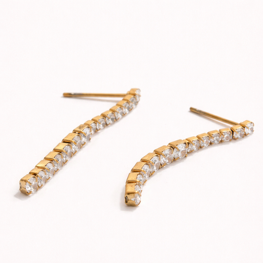 Ettie Earrings in gold, a curved ear climber lined with a row of graduated round crystals along the lobe.