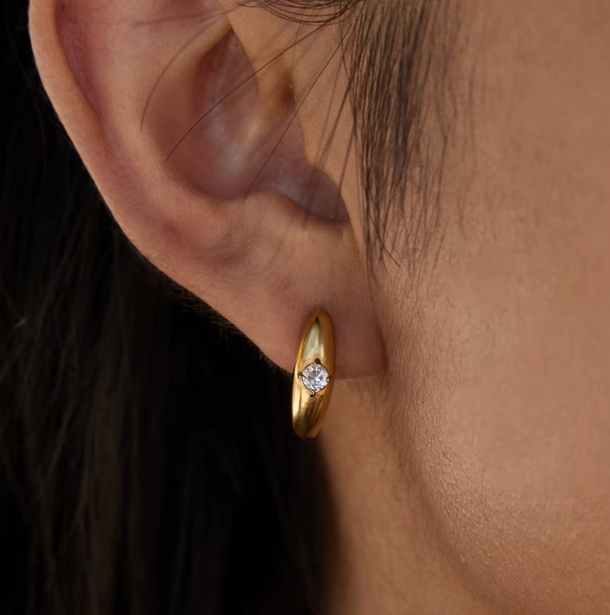 In close-up profile, the Everyday Drama EARRINGS reveal their sculpted gold hoop and bezel-set crystal.