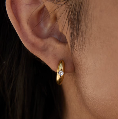 In close-up profile, the Everyday Drama EARRINGS reveal their sculpted gold hoop and bezel-set crystal.