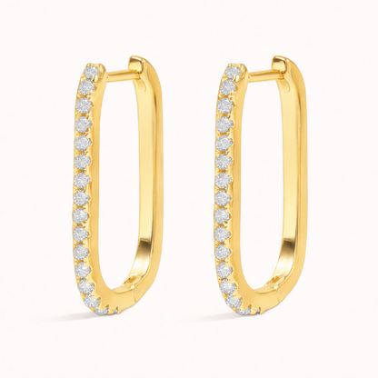 Fair Game Earrings form an elongated oblong hoop lined with pave crystals along one edge, shown here in polished gold.