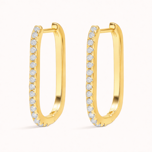 Fair Game Earrings form an elongated oblong hoop lined with pave crystals along one edge, shown here in polished gold.