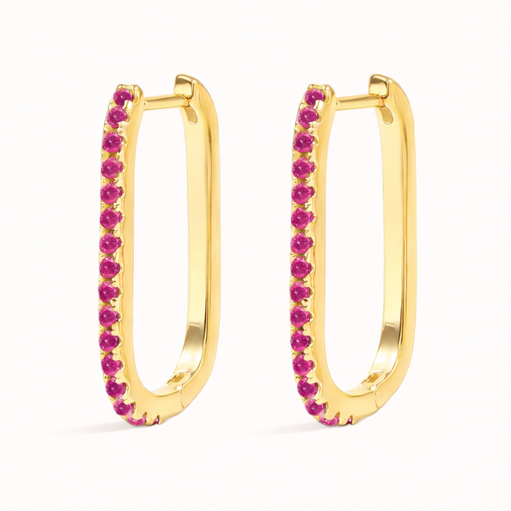 Fair Game Earrings appear here with vivid pink pave stones tracing the inner edge of their elongated gold oblong hoop.