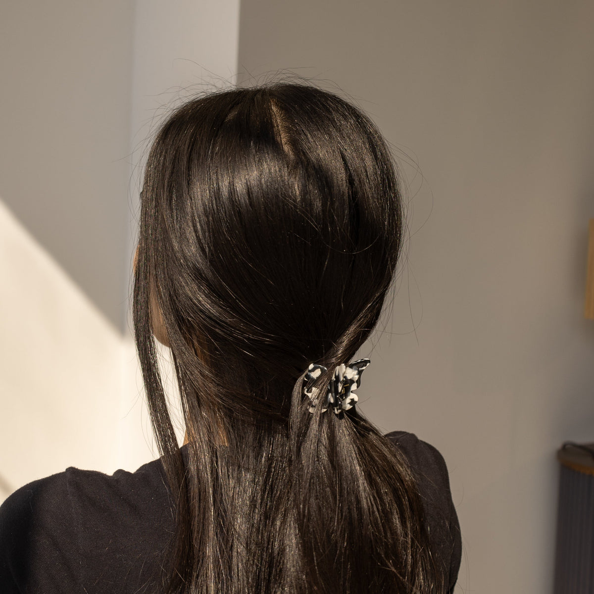 Falling For You Butterfly HAIR CLIP's black and white cow-print clip worn in half-up dark hair, in sunlight.