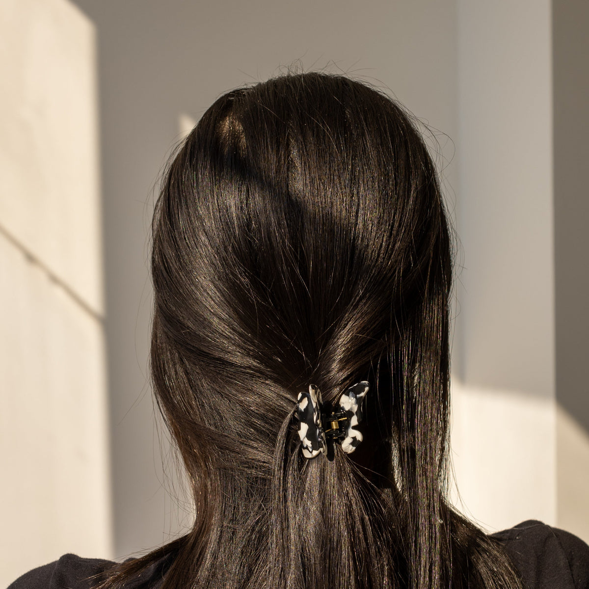 Falling For You Butterfly HAIR CLIP's black and white cow-print clip worn in dark hair, close-up view.