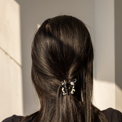 Falling For You Butterfly HAIR CLIP's black and white cow-print clip worn in dark hair, close-up view.