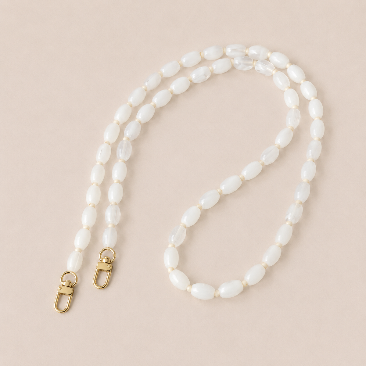 Folie à Trois Fennel long wholesale phone chain in white oval beads with cream spacers and gold clasps, laid flat on a cream background.