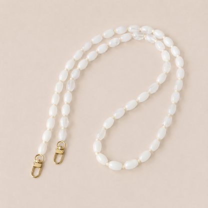 Folie à Trois Fennel long wholesale phone chain in white oval beads with cream spacers and gold clasps, laid flat on a cream background.